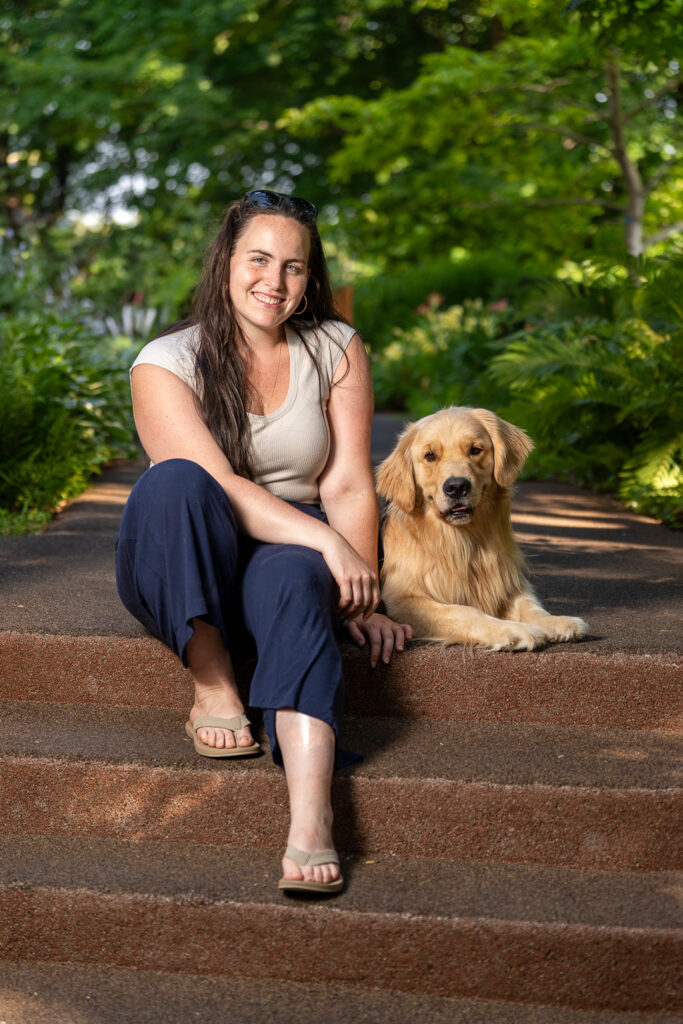 Marie-Danielle assise dans les marches accompagnée de son chien, Cooper.
