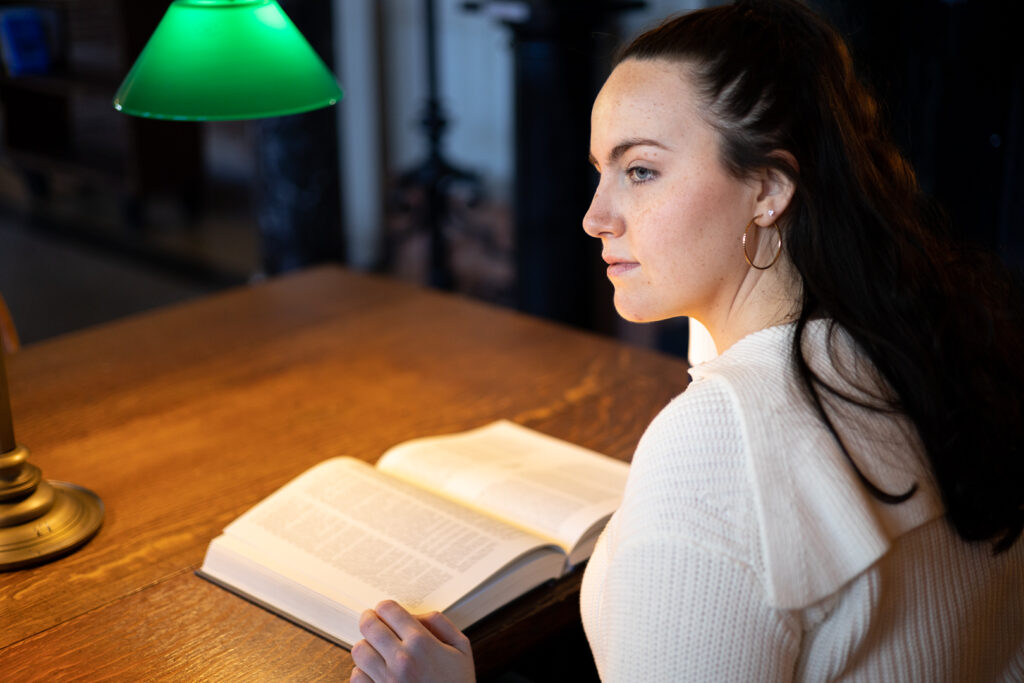 Marie-Danielle, votre photographe, qui fixe au loin, avec un livre à la main, à la Boston Public Library